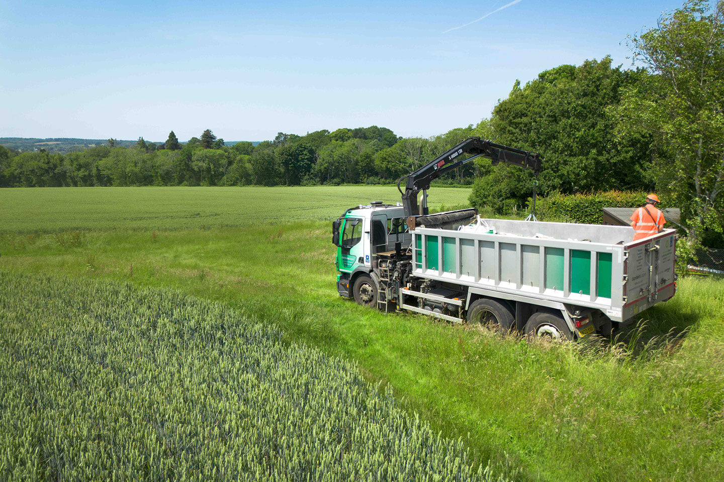 Truck with a crane in a field, likely for agricultural work.